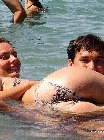 A smiley topless broad in a bikini, with some dude behind her, both of 'em lookin' right into the fucking lens while grinnin' like douchebags.