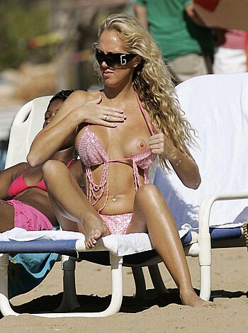 A naked blonde slut sits her fat ass down on the beach in a tiny thong, spreading her legs wide open so anyone can see her hairy twat and pink pussy lips.
