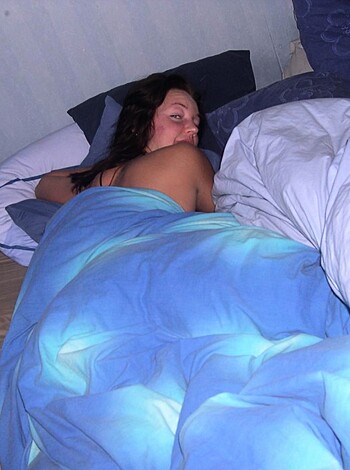 A fucking bitch is laid out nude with a blue-assed sheet covering her ass on some shitty bed.