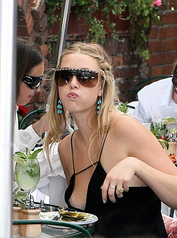 A chick with tits and ass hanging out at a shithole food joint, sporting some dumb-ass shades, looking like she's about to blow a load of fuckin' air.