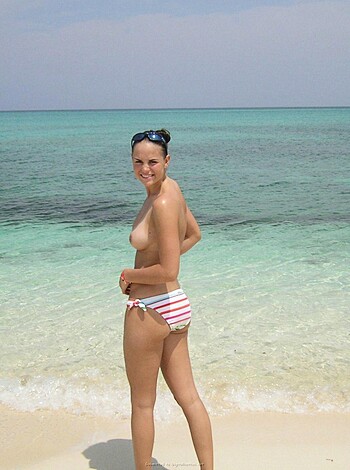 "A busty blonde chick wearing barely any clothes strolls down the shore, ass cheeks glistening in the sun."
