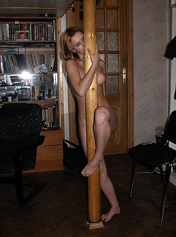 A nude bitch with her tit hanging out and gripping a stripper pole.
