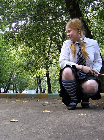 A busty blonde chick with thigh-high stockings and a tight mini skirt is dropping to her knees for some cock on the sidewalk.