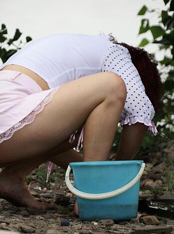 Here's the description of a bitch taking a shit, posing with her ass and legs, dressed in some pink shit and white blouse.