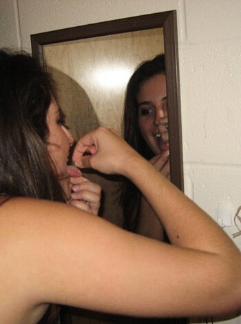 A hot chick sucking on her thumb while checking out her own reflection.