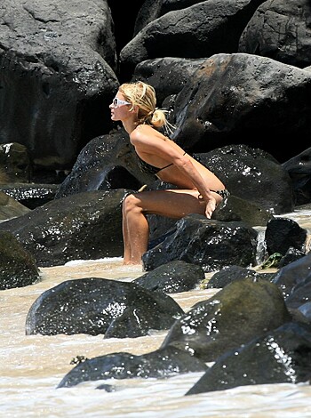 A topless chick is getting off while washing herself near the shore with her tits out and water splashing all over the place.