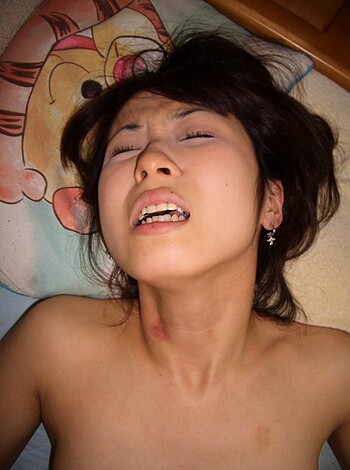 A nude chick is spread eagle on her back, with her mouth wide open and her face contorted in a scream, while an asshole snaps a picture of her.