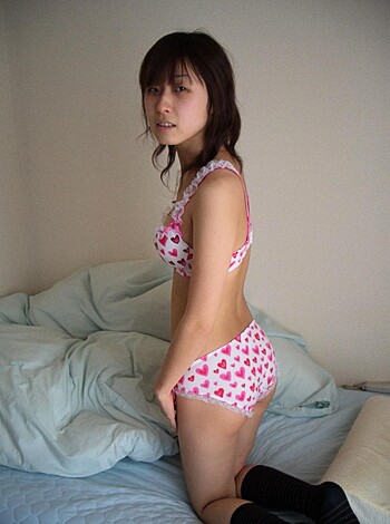 A slutty bitch, lying on some sheets, with only her panties and bra on. She's got tits and legs in clear view, and it ain't hard to see why.