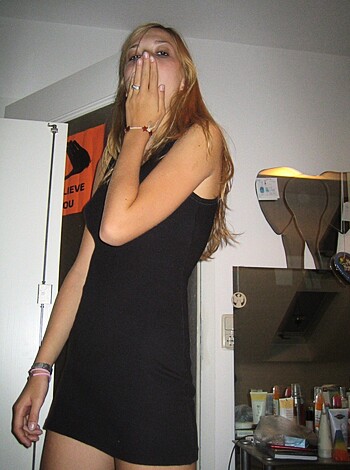 Here's a vulgar description of a picture of a chick rubbing her face while looking at the camera in some bitch's bathroom, with a black dress on and shit, probably taken during fucking night time or some shitty lit area.