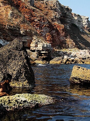 Here's a fuckin' picture of a nekkid dude swimming in the ocean, with some rocks in the background.