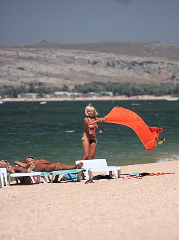 Fucking hot chick on the beach showing off her tits and ass with that fucking tight bikini, while she fucking holds up some stupid fucking towel like a retard.