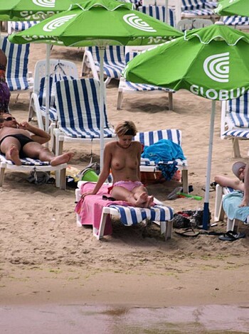 The image shows hot babes wearing tiny bikinis laying their asses down on plastic beach chairs, enjoying the sun and fucking each other up for your viewing pleasure.