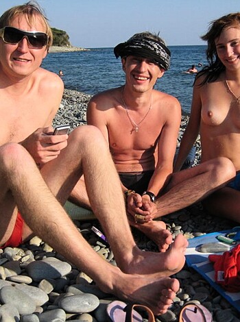 "Here's three hot babes on the beach, one in a skimpy bikini while her dude is shirtless with his sweet shades on and they're hanging out with some other random bro who's fully dressed."
