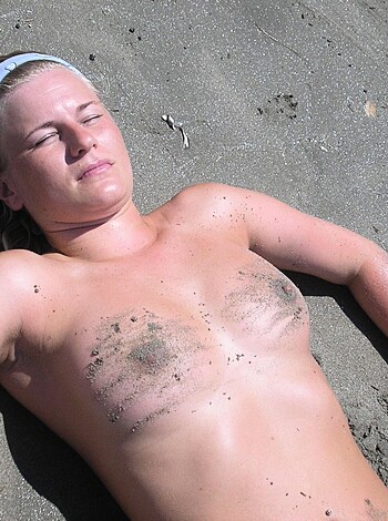 The naked chick is laid out on some fucking beach sand.