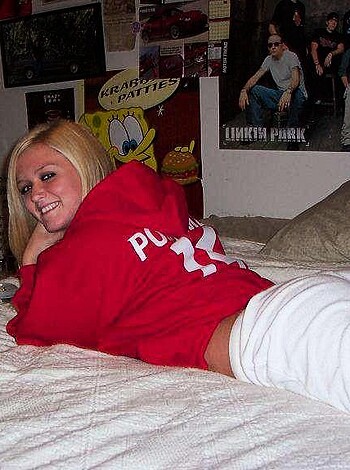 Laying naked woman with big tits, drenched in sweat and cum, sprawled out on a fluffy white bed.