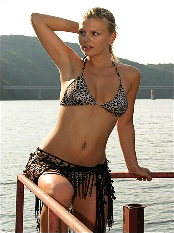 A busty blonde chick in a skimpy bikini, striking a pose for the camera with her rack on full display.