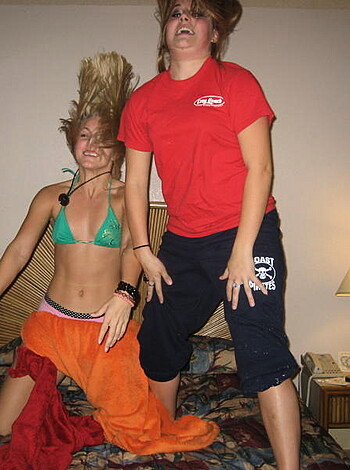 Fucking hell, man! Check out these two hot-ass hoes, both wearin' just their fuckin' bike tops in some bitch's bedroom, and one of 'em is laughin' like a goddamn psycho or somethin'. I mean, jesus fuckin' christ, who the hell takes a pic of shit like that?!