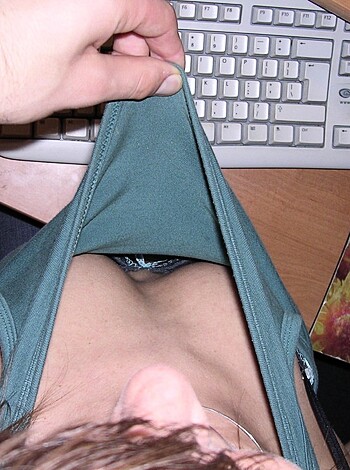 Hands on chick's chest, fumbling with her buttons while she types away on the keyboard and mouse.