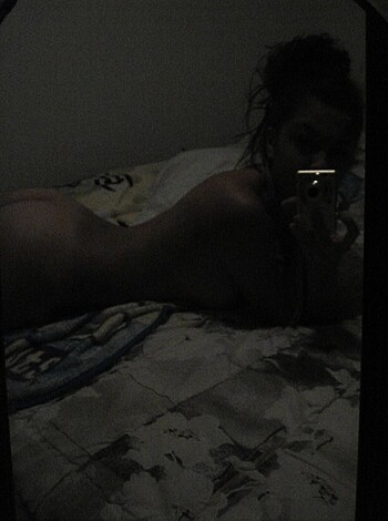 Here's the vulgar description of the image: "Bare-assed bitch taking a selfie while her ass hangs out of some random guy's bed."