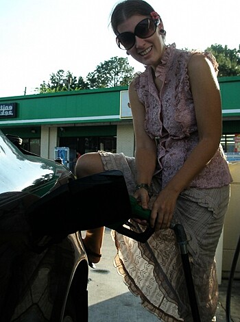 A bitch fills up her tank while showing off her tits and arms, all while fuckin' smokin' a cigarette, motherfucker.