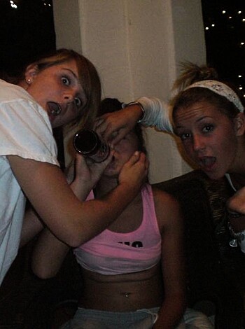 Two chicks covering each other's mouth with their hands, while one is looking shocked.