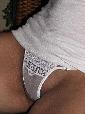 This image shows a bitch's bare legs and fucking thighs, with her white shirt barely hanging on her body like she just got out of bed and forgot to put pants on.
