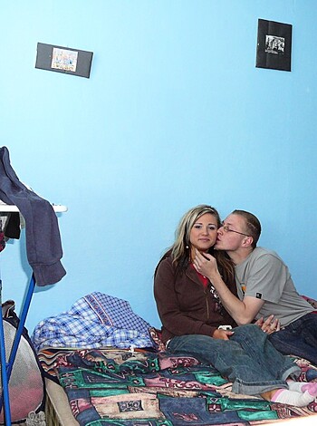 Here's a fuckin' image of a couple gettin' it on in their goddamn bed, with tongues swappin', lips locked, and fingers gropin'.