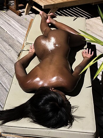 A naked bitch is lounging on a fucking towel that's covered in fucking baby oil, probably at some rich motherfucker's beach house or resort.