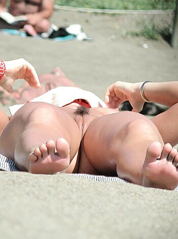 Here's a fucking hot bitch, stretched out on a goddamn beach towel, her boobs spilling out of that tight little bikini top she's got on.