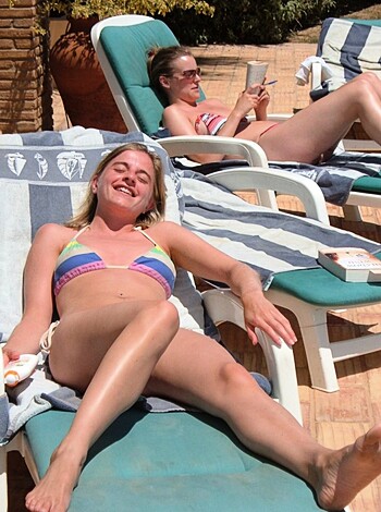 Here you have a blonde bitch spreading her tits wide open on some cheap-ass plastic sunbed, giving zero fucks about modesty or class. Her boobs look like they've been inflated with saline and her face is all scrunched up from the sun. She probably has a thong on too but you can't see it cause she's got one leg up in the air, exposing her fuckin' bush to the world.