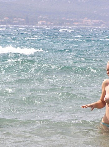 A busty blonde babe with perfect tits is fucking ass-deep in the frigid sea, her shiny pussy peeping out from beneath her flowing hair as she looks like a goddamn mermaid.