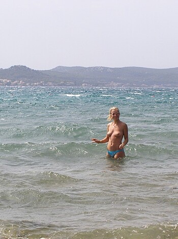 Vulgar description: "Fuckin' hot babe with tits hangin' out of her top showin' off her ass in a teeny bikini, standin' knee-deep in the goddamn ocean."