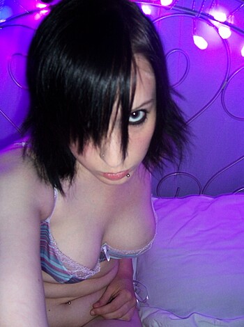 """
A chick sits on a bed half-naked, showing off her knockers in the shadows.
"""