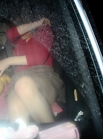 A busty bitch in a black dress and fuck me pumps, leaning back in the driver's seat of her sports car while exposing her milky white thighs and tits.