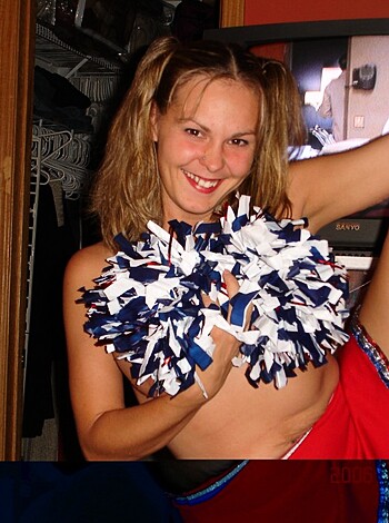 """
Naked chick in a pom-pom bra, showing tits and ass while giving the camera a smug smile. 
"""