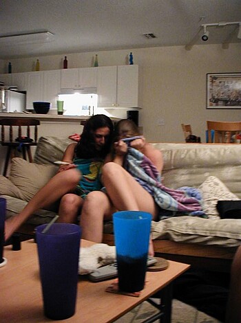Image of two chicks making out on a couch, sucking face and getting cozy with each other.