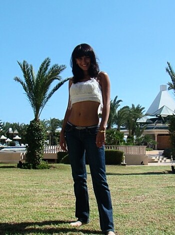 Here's a fucking hot chick, dressed in tight ass jeans and a skimpy bikini top, posing out on the street like some kinda damn hottie.