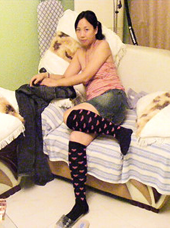A naked chick lying on her side with her ass sticking out and feet dangling off the bed while she rubs one out.