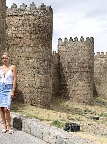 A fucking hot babe poses beside a goddamn ugly brick structure.