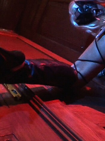 The image is of a busty broad, with a sexy-ass outfit on and one barely there boot up on her foot, getting all dirty down low with a stiletto dangling from her toes.