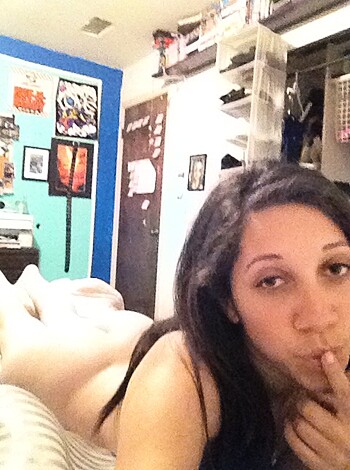 A fat chick lies in bed, trying to cover her tits.