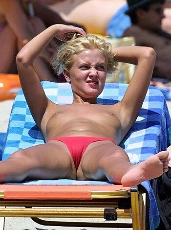 Fucking hot babe showing her perky tits while chilling on the sandy shore, with an ice-cold beer in hand.