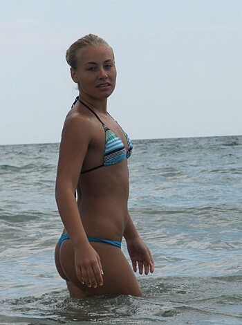 A hot, busty chick with a tight bikini is showing off her ass and tits as she stands in the water with her back to you, checking out some dudes on the beach probably wondering why you ain't one of them.