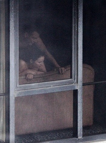 A fucking nude couple is standing hand-in-hand in a dark room while sucking each other's dicks off.