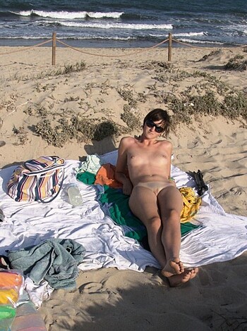 A bare-assed dude lying on the sand.