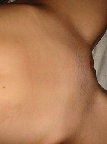 A woman has stripped off her panties to show her naked pussy for the camera, while sitting on a bed or couch.