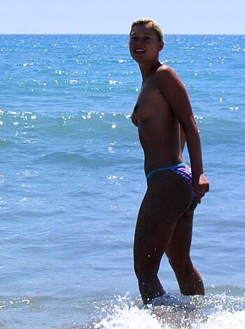 Vulgar description of image: "Look at this fucking hot chick with her tits hanging out, standing in some goddamn ocean water."