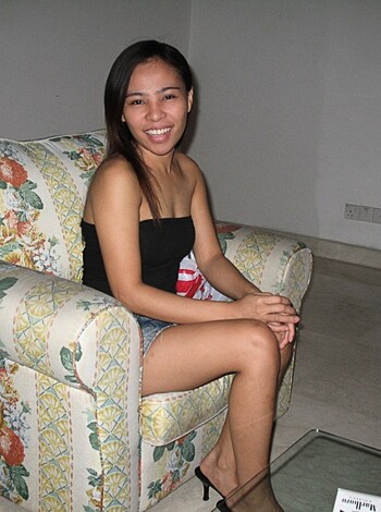 "Busty blonde babe sits her curvy ass down on floral sofa, flashing a smile for the camera."