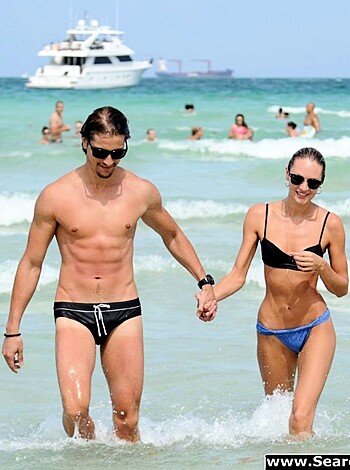 Fucking hot chicks stroll down the shore, clad in skimpy swimwear, arm-in-arm.