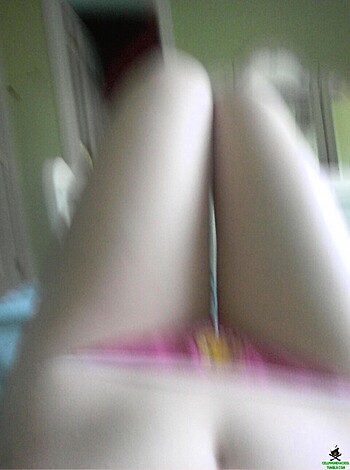 A naked chick in her panties and bra, spread eagle on the bed with her legs crossed.